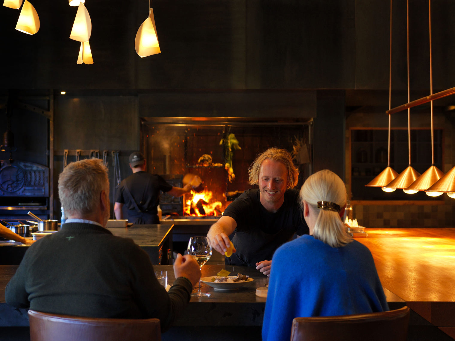 A chef serving guests at the Flock Hill fire kitchen, a Canterbury Trails high country gourmet experience