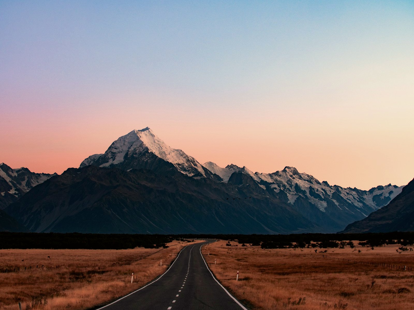 The open road through the golden Mackenzie Country toward the Southern Alps