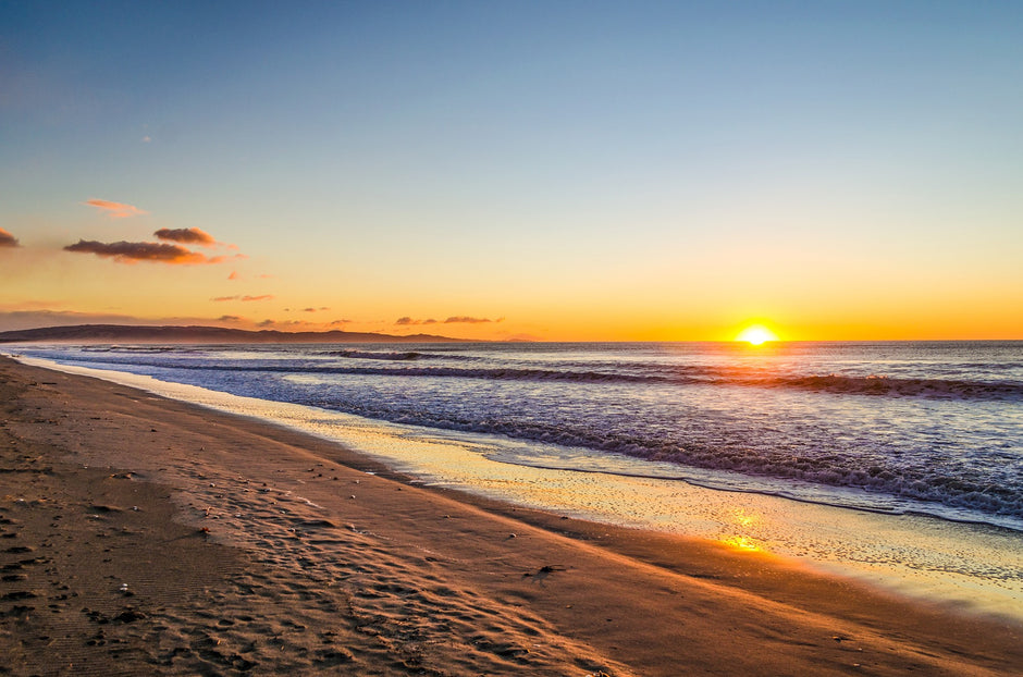 Sunset over a beach with waves and a clear sky