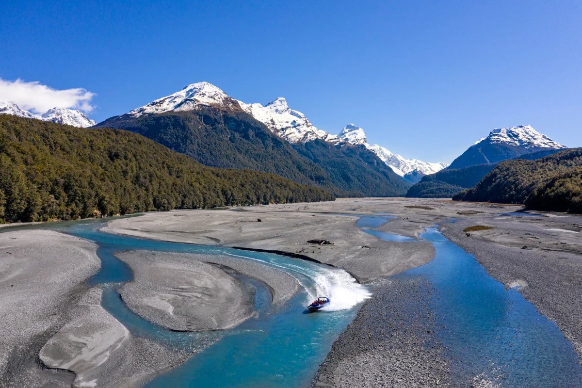 A jet boat on the braided Dart River, with the peaks of Mount Aspiring National Park beyond