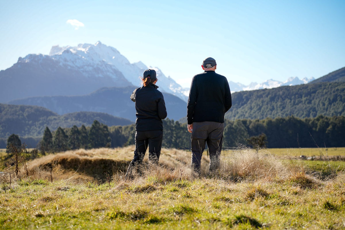 Two travellers looking toward snow-covered mountains across the flats near Paradise