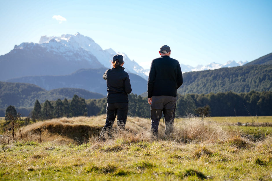 Two travellers looking toward snow-covered mountains across the flats near Paradise