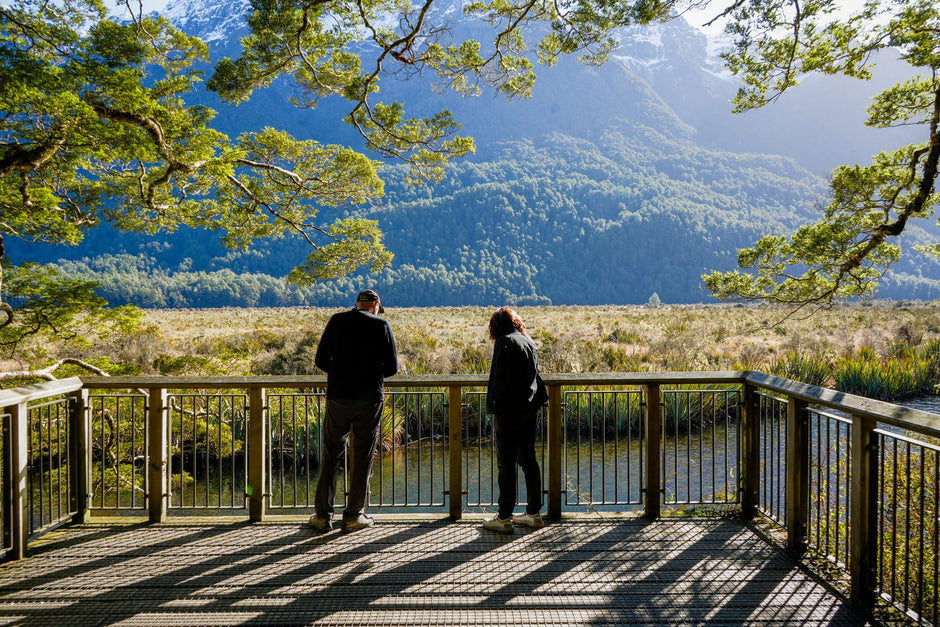 Two travellers at the Mirror Lakes viewing platform on the Milford Road, looking out over the water