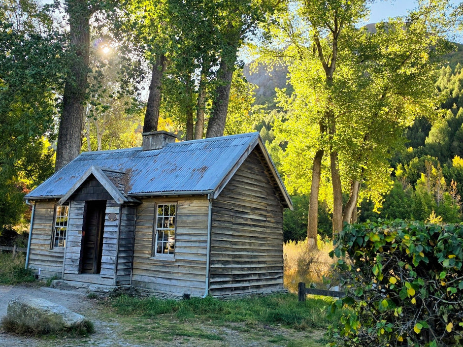 A restored miner's hut beneath autumn poplars in Arrowtown