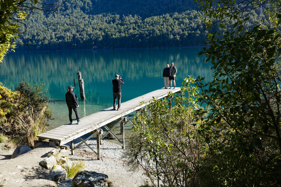 The jetty at Bob's Cove above clear turquoise water, with walkers looking out over Lake Wakatipu