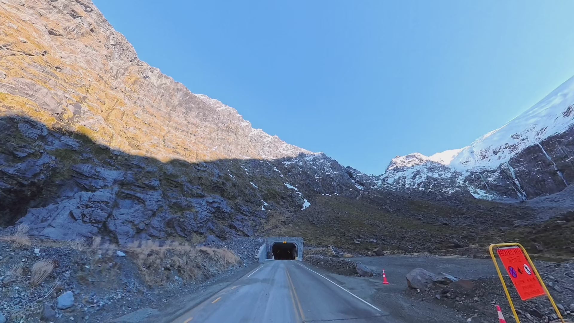 The road climbing to the Homer Tunnel beneath sunlit cliffs